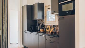 Een moderne keuken met donkere kastjes, een ingebouwde oven en een raam boven de spoelbak.