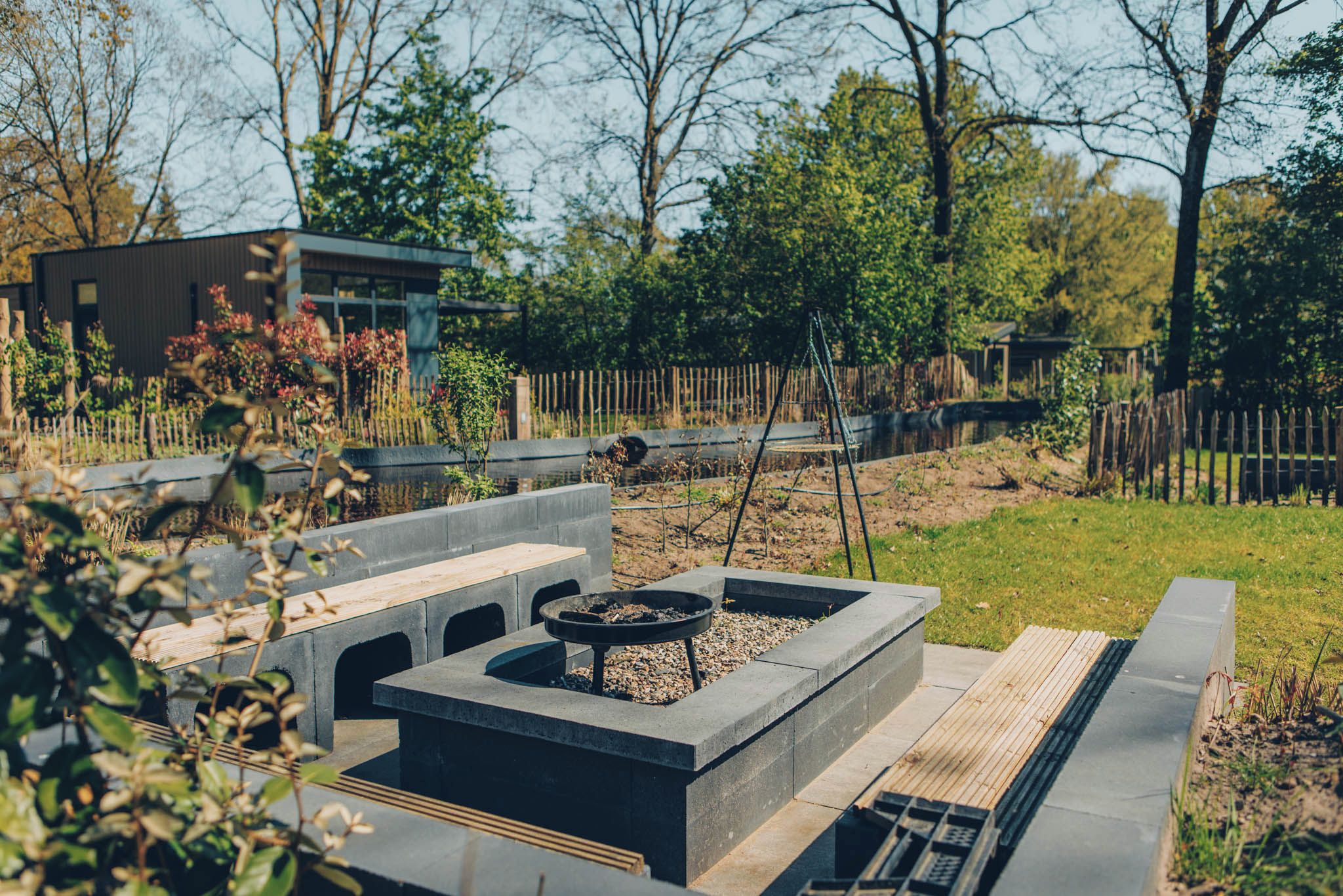 A modern outdoor seating area with concrete planters, a fire pit, and a wooden deck.