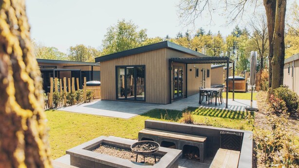 Una casa moderna con un patio, mobiliario exterior y una chimenea.