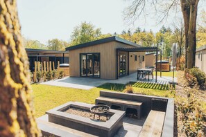 Moderni talo, jossa on patio, ulkotila istumiseen ja nuotiopaikka.