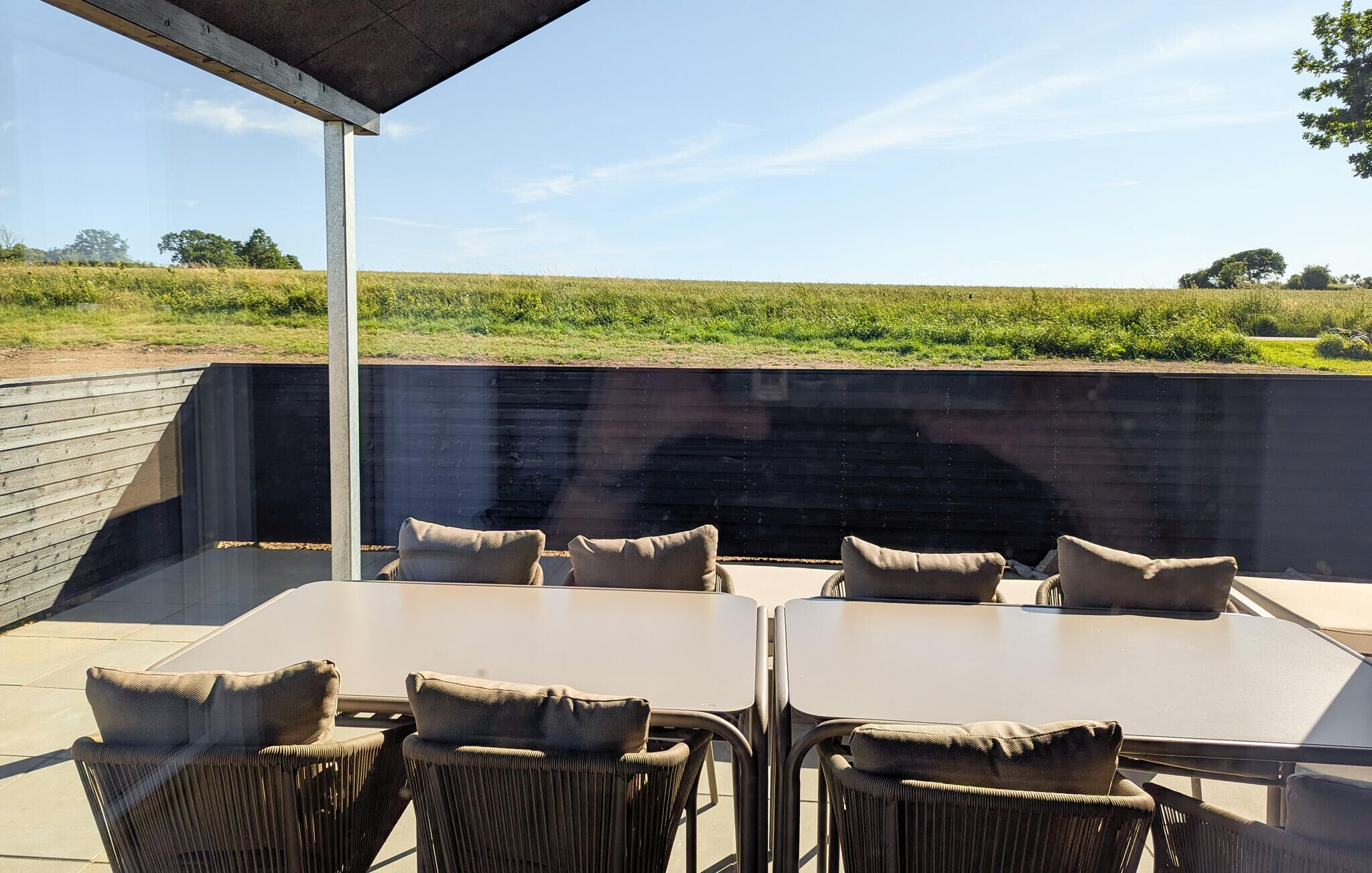Un patio al aire libre con una mesa y sillas, un muro de hormigón y vistas a un campo.