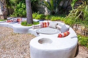 A curved outdoor seating area with cushions and a central round table.