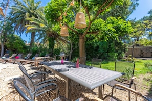 Un espace de restauration en plein air, avec une table et des chaises, entourĂ© de verdure et dâun arbre.