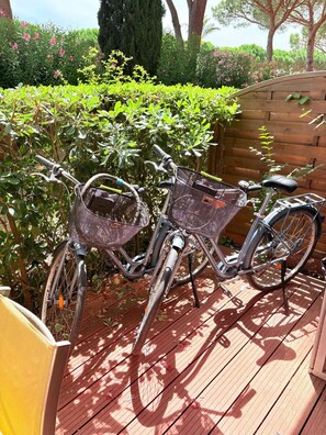Ein Fahrrad steht auf einer Holzterrasse, vorne ist ein Metallkorb befestigt.