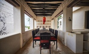 A dining area with a long table, chairs, and a red hanging light fixture. - Mnarani House, Luxury 4 Bedrooms Villa with pool in Shela, Lamu Island. (Shela)