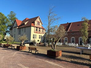 A traditional building with a red-tiled roof, a courtyard with outdoor seating, and a parked car. - Stylish Art Nouveau apartment in an idyllic rural setting (Zerbst/Anhalt)