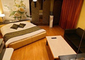 A hotel room with a bed, a sofa, a small table, a remote control, a water dispenser, and a wall-mounted phone. - HOTEL TIGER & DRAGON - Adults Only (Gifu)