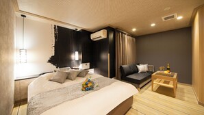 A modern bedroom with a large bed, a sofa, a small table, and an air conditioning unit. - HOTEL TIGER & DRAGON - Adults Only (Gifu)