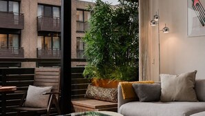 Een moderne woonkamer met een glazen salontafel, een bank, een stoel en een grote plant.