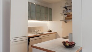 Een moderne keuken met witte kasten, een houten aanrecht en twee houten krukken.