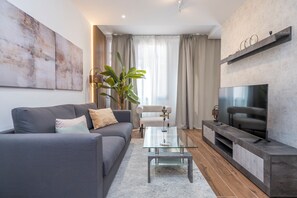 Uma sala de estar moderna com sofá, mesa de centro, TV e uma planta.
