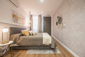A bedroom with a bed, bedside lamp, wall art, and a wardrobe. - Apartamentos Príncipe de Canalejas (Ma)