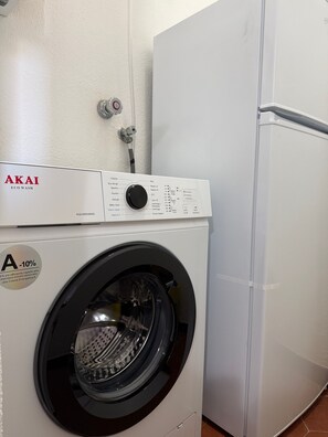 Una lavadora de carga frontal con un panel de control, una válvula de entrada de agua y una pared blanca.