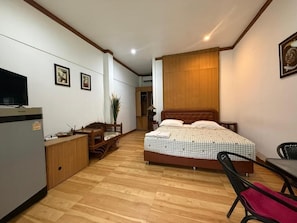 Un dormitorio con cama, escritorio, silla, televisor y armario.