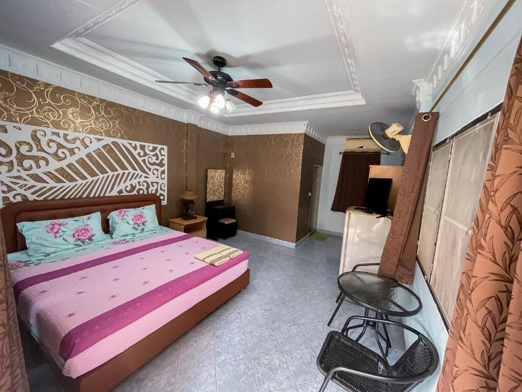 Ein Schlafzimmer mit Bett, Deckenventilator, Nachttisch, Stuhl und Kleiderschrank.