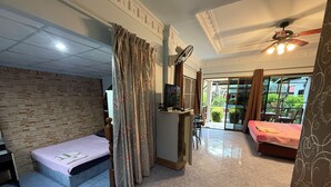 Una habitación con cama, escritorio, ventilador y vistas al exterior.