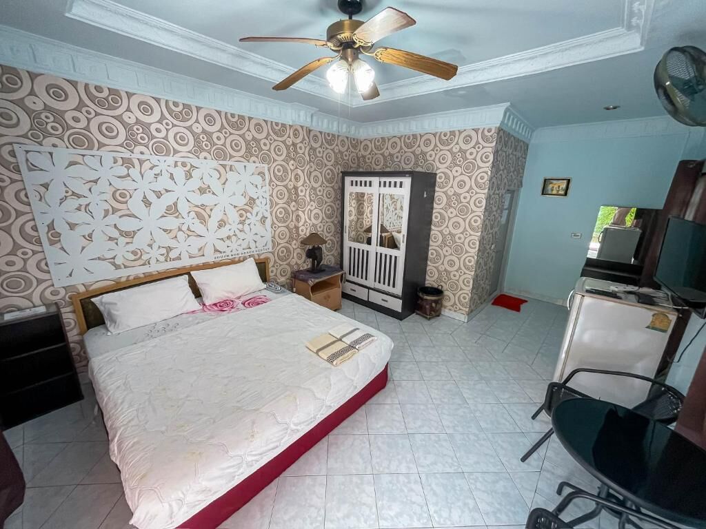 Ein Schlafzimmer mit einem Bett, einem Deckenventilator, einem Kleiderschrank, einem Schreibtisch und einem Stuhl.