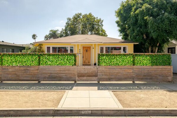 Une maison à deux étages avec une porte d’entrée, une clôture en bois et une allée pavée.