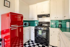 A kitchen with white cabinets, a red Galanz refrigerator, a black stove, and a checkered floor. - Lemonade & Sunshine Near Downtown Oceanside (Oceanside)