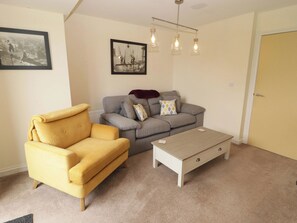 A living room with a yellow armchair, grey sofa, and a white coffee table. - Twyni Bach (Burry Port)