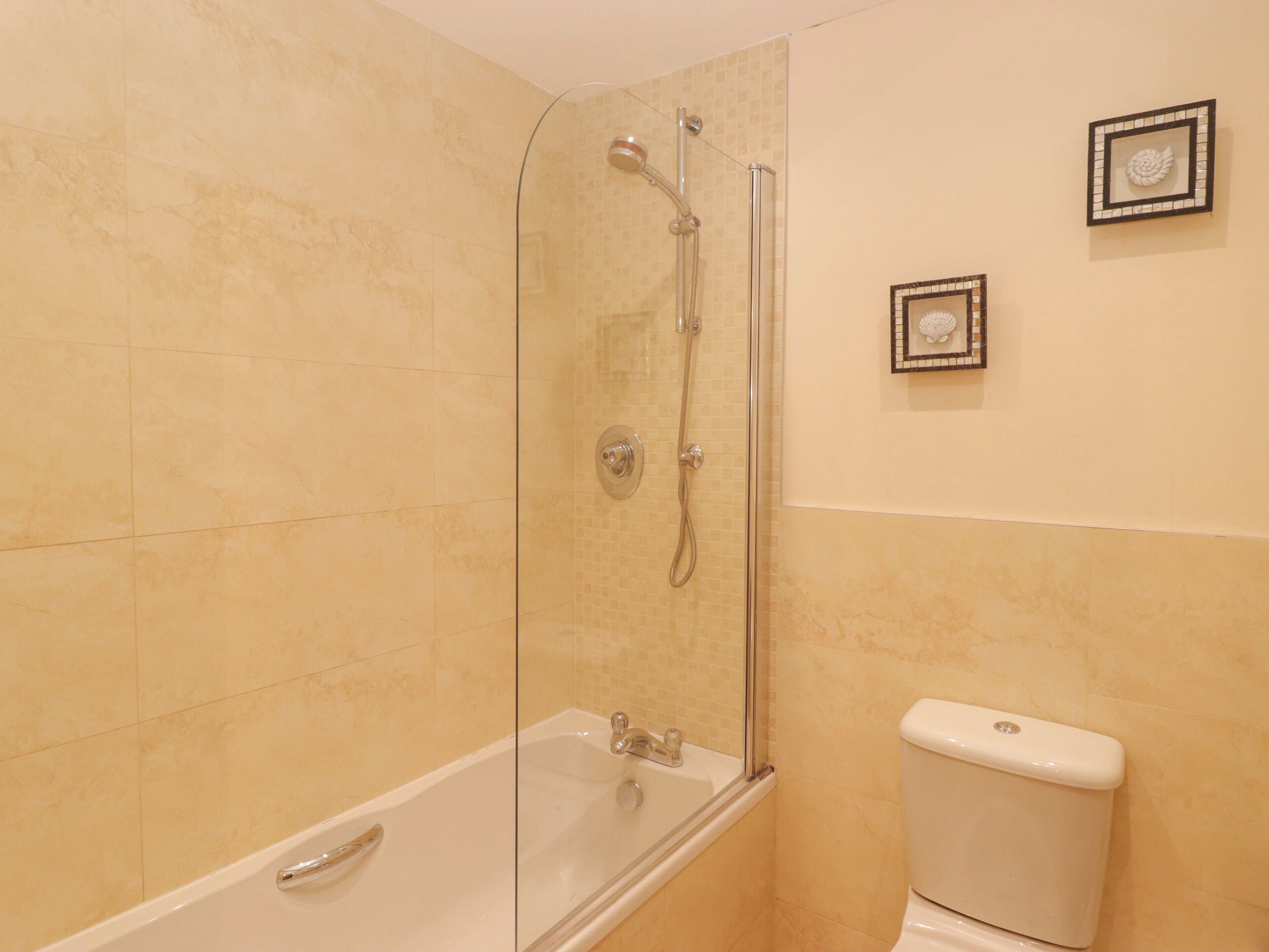 Een badkamer met een douchecabine van glas, een bad en een toilet.