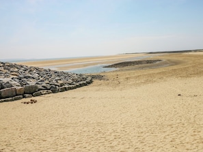 A beach with a rocky breakwater and a sandy shore. - Twyni Bach (Burry Port)