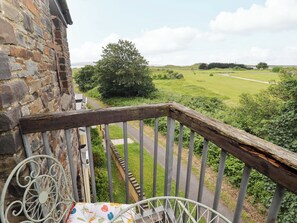 A balcony with a stone wall, a metal railing, and a view of a green landscape. - Twyni Bach (Burry Port)