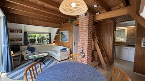 Un accogliente interno di una baita con zona living, tavolo da pranzo e cucina.