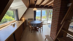 A dining area with a round table and chairs, a hanging light fixture, and a view of the outdoors through a glass door. - Casa Ines with Lake Maggiore View (Villaggio Olandese)