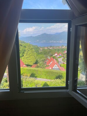 Ein Fenster mit Blick auf eine grüne Landschaft und Gebäude mit roten Dächern.