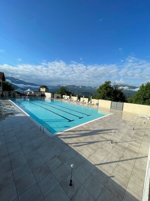 A swimming pool with clear blue water, surrounded by tiled flooring and lounge chairs. - Casa Ines with Lake Maggiore View (Villaggio Olandese)