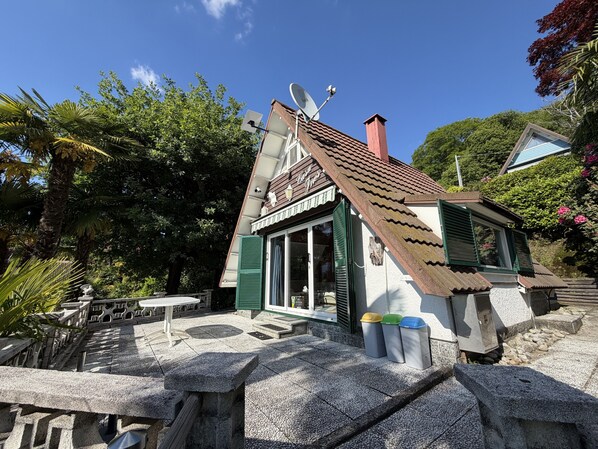 A small building with a sloped roof, a satellite dish, and a trash bin area. - Casa Ines with Lake Maggiore View (Villaggio Olandese)