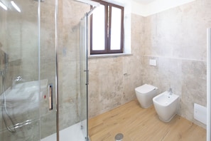 Un bany amb un envà de dutxa de vidre, un vàter i un lavabo.