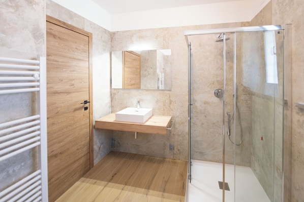Ein modernes Badezimmer mit einem Holzwaschtisch, einer Glasdusche und einem großen Spiegel.