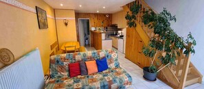 A cozy living room with a sofa, a dining area, a kitchen, and a staircase. - Holiday Home “Gîte 851 in the Lake District” with Wi-Fi (Bonlieu)