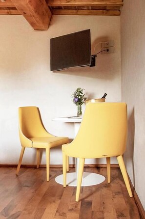 A room with two yellow chairs, a small table with a vase, and a flat-screen TV mounted on the wall. - Agriturismo Montecolombo by Il Ritorno (Ancona)