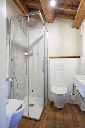A bathroom with a glass-enclosed shower, a white toilet, and a wooden floor. - Agriturismo Montecolombo by Il Ritorno (Ancona)