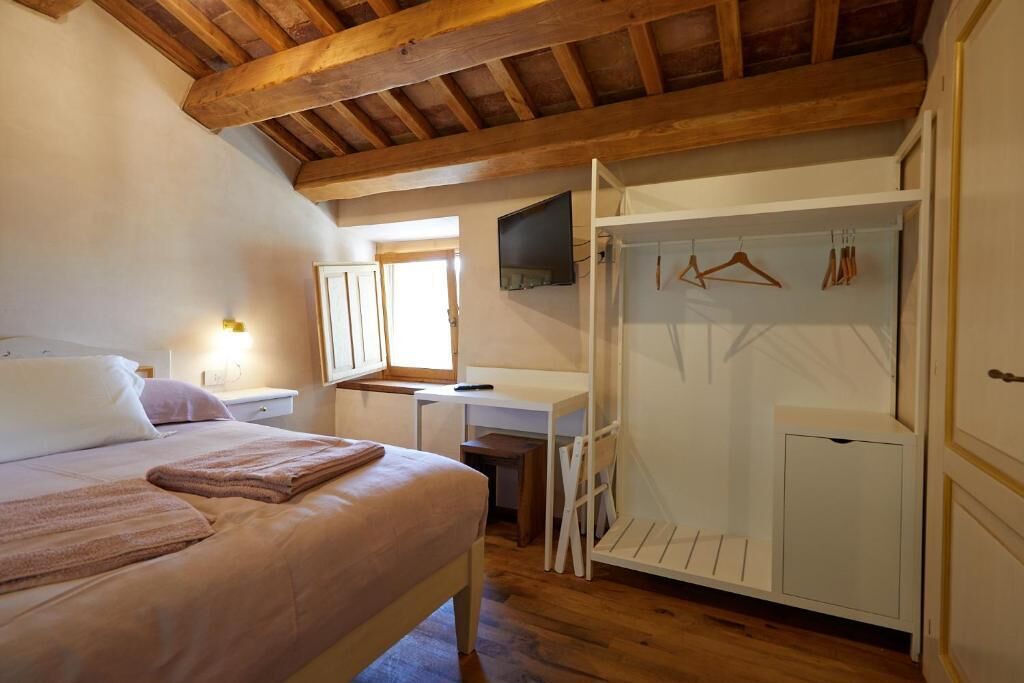 A bedroom with a bed, a desk, a TV, and a walk-in closet.