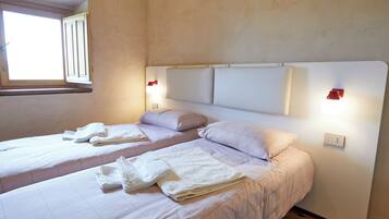Quarto com duas camas, cada uma com cabeceira, janela e luminárias laterais.