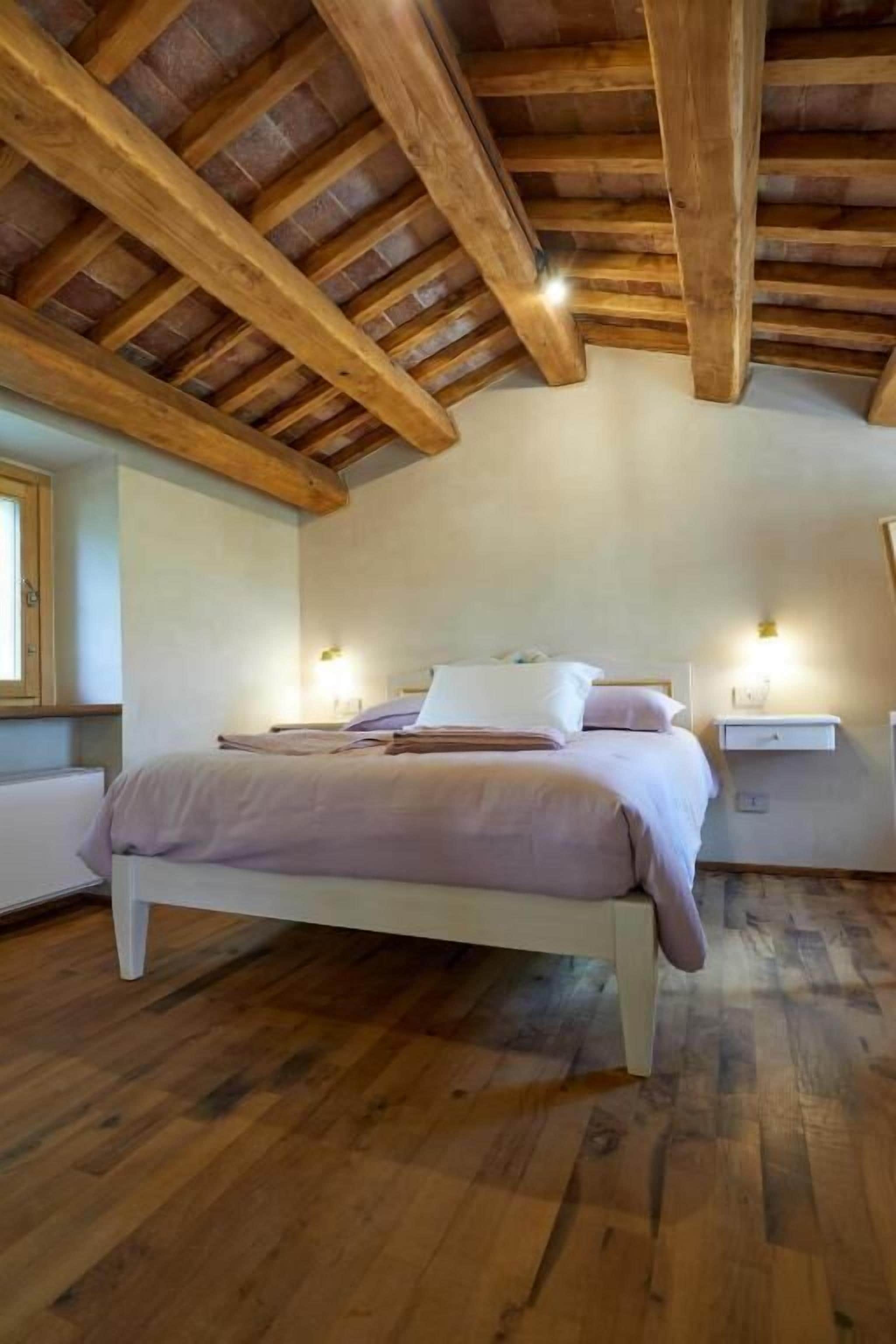 Un dormitorio con techo de madera, una cama con estructura blanca y dos mesitas de noche.