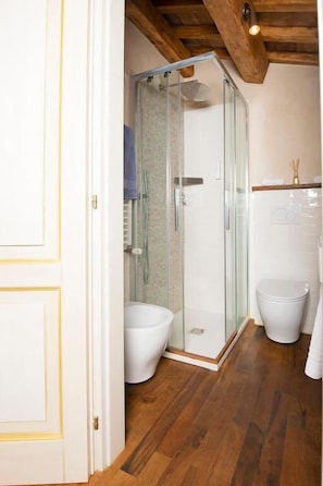 Un bany amb dutxa de vidre, un vàter blanc i un lavabo blanc.