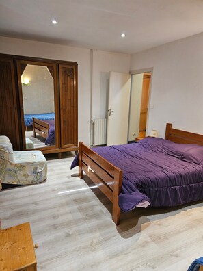A bedroom with a wooden bed, a wardrobe, a chair, and a mirror. - Holiday Home "Gîte 1265 in the Lake Region" with Shared Garden and Wi-Fi (Bonlieu)