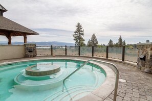 Ein Pool mit kreisförmigem Design, umgeben von einer Steinmauer und einer Holzpergola.