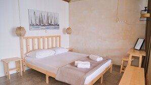 A wooden bed with white linens, a woven rug, and a painting of sailboats on the wall. - Rota Klima (Milos)