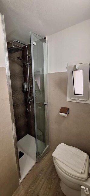Une salle de bain avec une douche à parois de verre, des toilettes et un porte-serviettes.