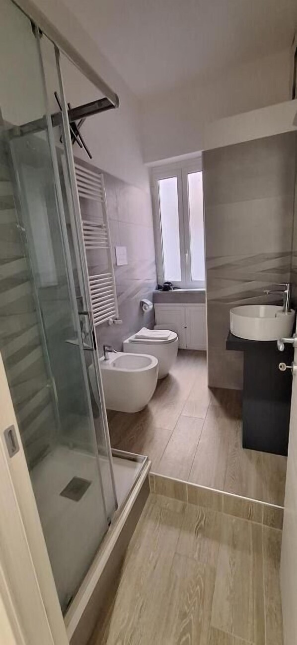 Une salle de bain moderne avec une douche à parois de verre, un bidet, un lavabo et des toilettes.