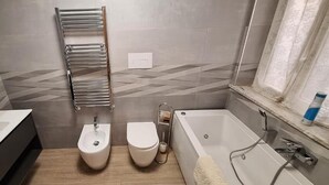 Ein modernes Badezimmer mit Toilette, Bidet und Badewanne.