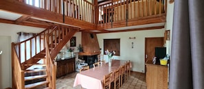 Un coin repas agrémenté d’un escalier en bois, d’une cheminée et d’une table à manger dressée pour six personnes.