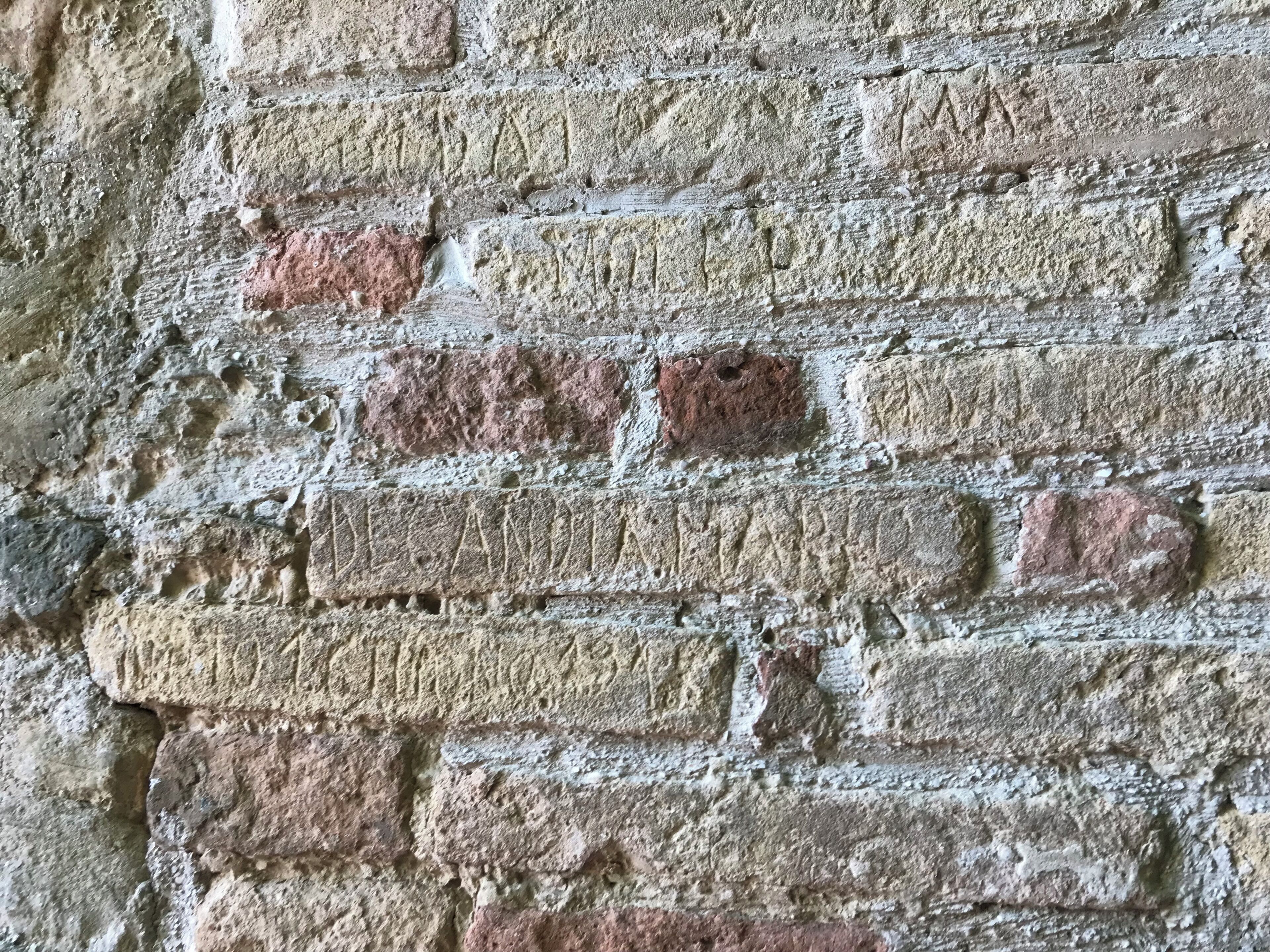 Un gros plan d’un mur de briques, où l’on peut voir les joints de mortier et quelques zones de décoloration.