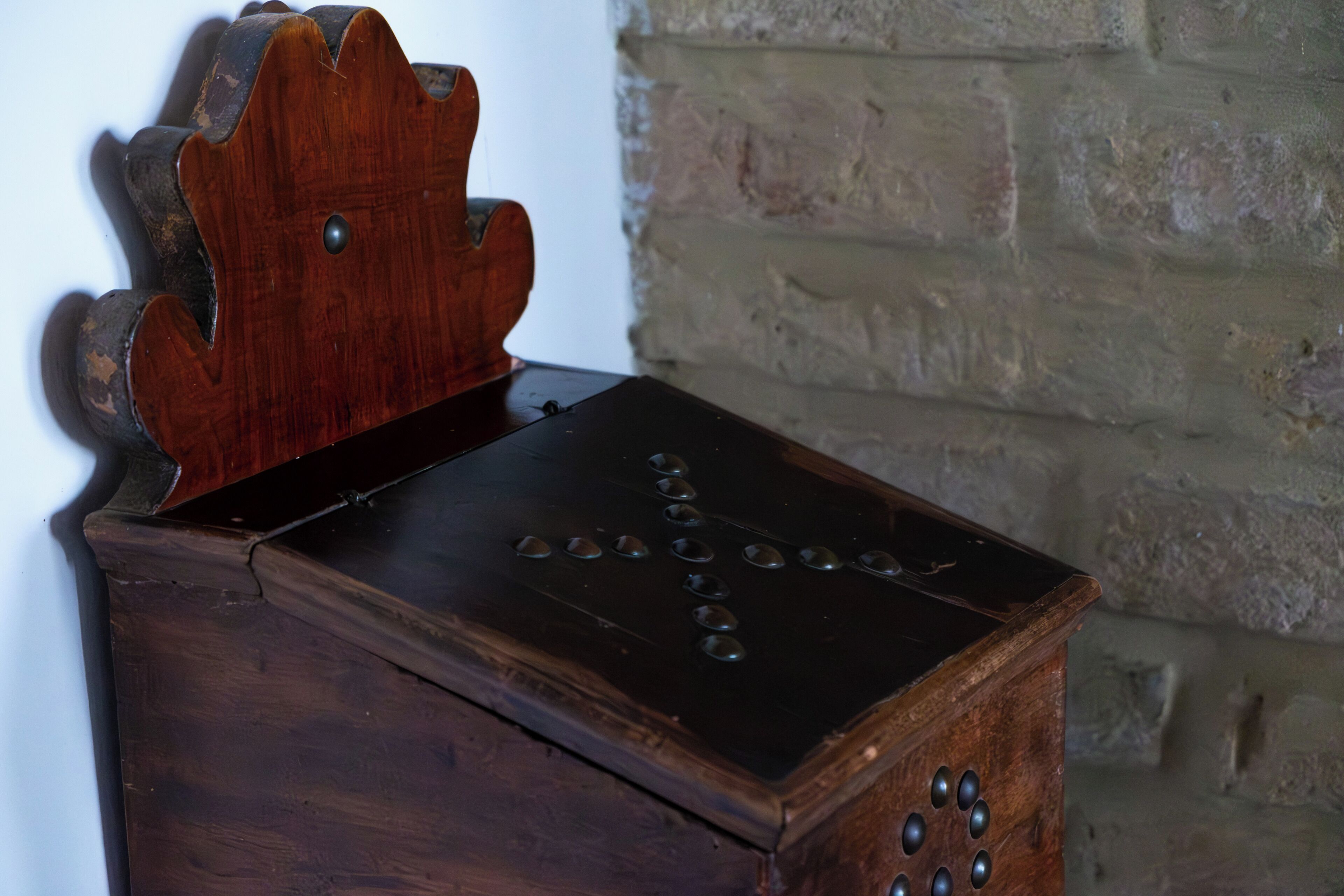 Een houten kist met deksel, voorzien van decoratieve details en klinknagels aan de zijkanten.